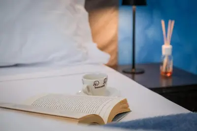 a book and a cup of coffee on a bed at Mocenigo Vatican Suites in Rome
