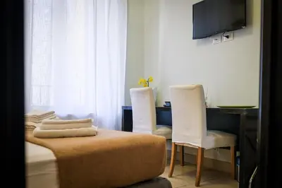 a room with two chairs and a bed and a television at Mocenigo Vatican Suites in Rome