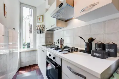 a white kitchen with a stove top oven next to a window at Tasso Street 102 in Rome
