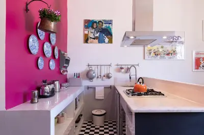 a kitchen with a pink wall and a stove at Rome As You Feel - Vittorio Colorful Design Apartment in Rome
