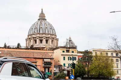 a white car parked in front of a building with a cathedral at GuestHost - Vatican Museums Cozy Flat x4 in Rome