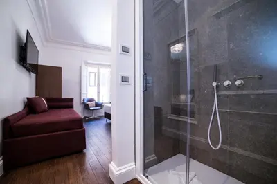 a bathroom with a glass shower with a red chair at Youroom Carrozze in Rome