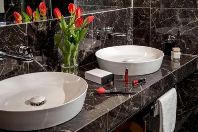 a bathroom with two sinks and a vase of flowers at Almaìt in Rome