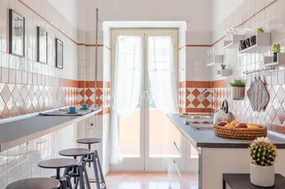 a kitchen with orange and white tiles and a counter with stools at Vatican Cozy Apartment with Terrace in Rome