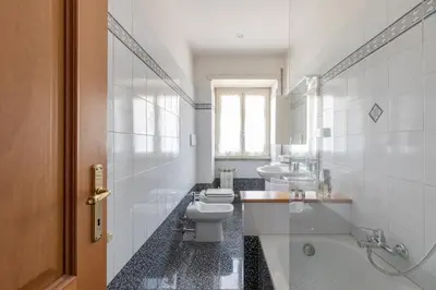 a bathroom with a toilet and two sinks and a tub at Vatican Cozy Apartment with Terrace in Rome