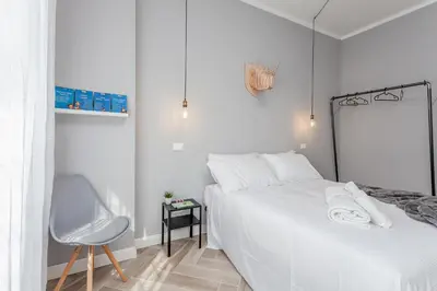a white bedroom with a white bed and a chair at Otium Fornaci San Pietro Vaticano Castel Sant'Angelo in Rome