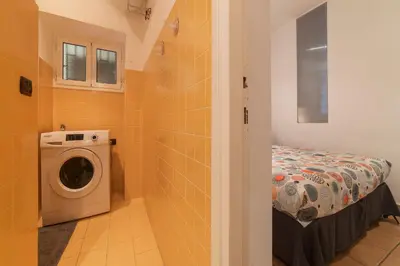 a bathroom with a washing machine and a bed at GuestHost - Colosseo & San Clemente Cozy Flat in Rome