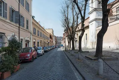 a cobblestone street with parked cars and buildings at GuestHost - Colosseo & San Clemente Cozy Flat in Rome