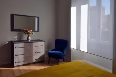 a bedroom with a dresser and a blue chair and a mirror at Rome Labicana Apartment in Rome