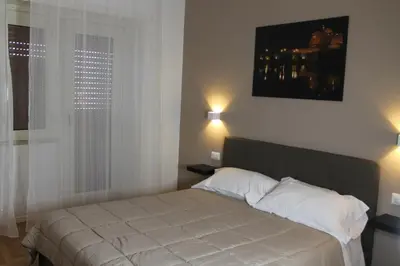 a bedroom with a bed with white sheets and a window at Roma suite Piramide in Rome