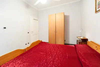 a bedroom with a red bed and a wooden cabinet at Mons Aureus Resort in Rome