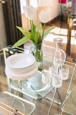 a glass table with a vase with white flowers and glasses at R.C. Cappellari Charming Campo de Fiori in Rome