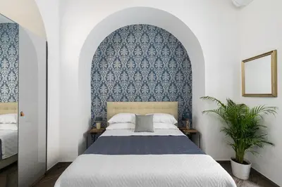 a bedroom with a bed with a blue patterned wall at Horti Sallustiani Roma in Rome