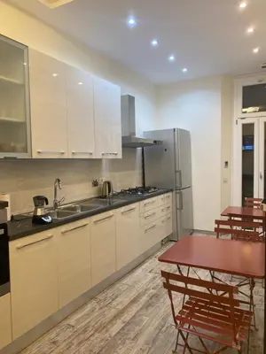 a kitchen with white cabinets and a red table at Zeus Inn - Una finestra sul Vaticano in Rome