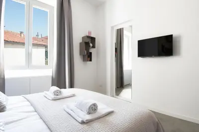 a white bedroom with two towels on a bed at 1 bdr apartments Ambio Suites Luxury Trastevere in Rome