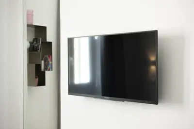 a flat screen tv hanging on a white wall at 1 bdr apartments Ambio Suites Luxury Trastevere in Rome
