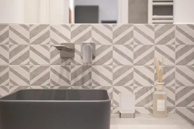 a bathroom with a sink and a tiled wall at 1 bdr apartments Ambio Suites Luxury Trastevere in Rome