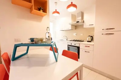 a small kitchen with a blue table and orange chairs at Rizzo St. Peter apartment in Rome