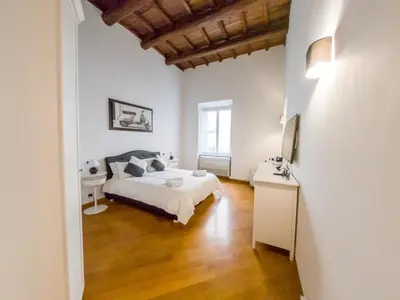 a bedroom with a white bed and a wooden floor at Pandy Suite in Rome