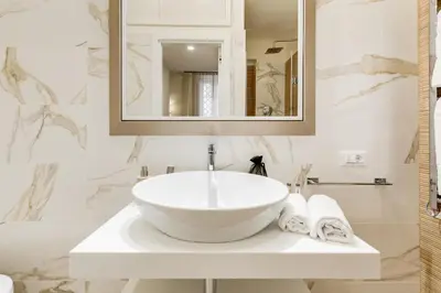 a white bathroom with a sink and a mirror at Trevi Chic House in Rome