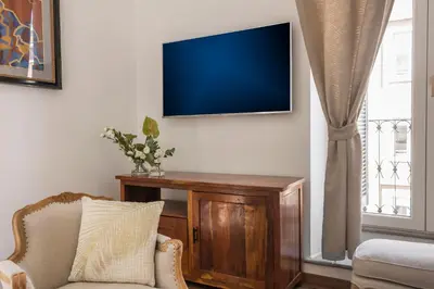 a living room with a couch and a tv on the wall at New! Spanish Step Design Apartment in Rome