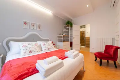a bedroom with a large bed with red sheets and a red chair at *****AmoRhome***** New Luxury apartment in the heart of Rome in Rome
