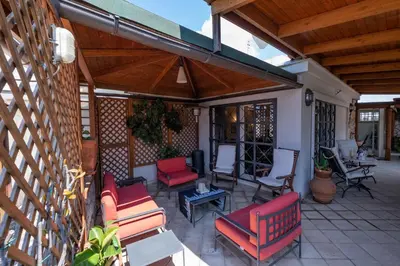 an outdoor patio with red chairs and a wooden roof at Amazing Penthouse with Terrace by Caracalla in Rome
