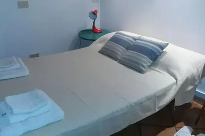 a white bed with two pillows and a lamp on a table at The heart of Trastevere in Rome