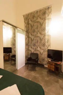 a room with two chairs and a wall with a wallpaper at Mr Frills in Rome
