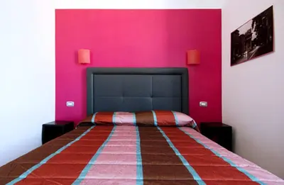 a bedroom with a bed with a pink wall at MF Hotel in Rome