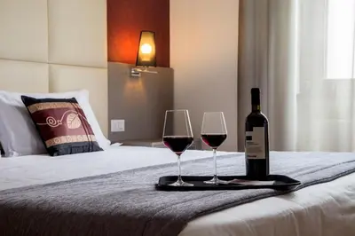 a bottle of wine and two glasses on a bed at Hearth Hotel in Rome