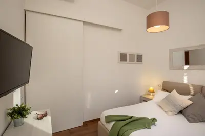a white bedroom with a bed and a couch at Fornaci Vatican Flat in Rome