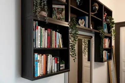 a black book shelf filled with books next to a door at St. Peter Central Rooms B&B in Rome