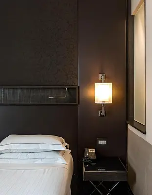 a bedroom with a bed and a lamp on a wall at Rome Times Hotel in Rome