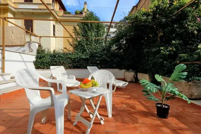 a patio with white chairs and a table with fruit on it at I Pini di Roma - Rooms & Suites in Rome