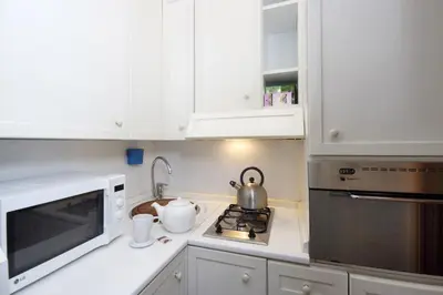 a white kitchen with white cabinets and a microwave at Frattina Apartments in Rome