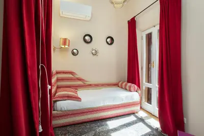 a bed with red curtains in a room with a window at Gambero Apartments in Rome