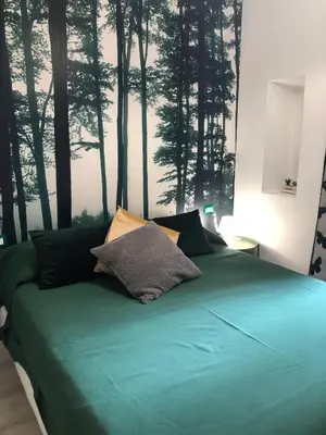 a bedroom with a green bed with trees on the wall at giolitti central room in Rome