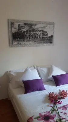 a bed with purple pillows and a picture on the wall at Orchids Apartment in Rome