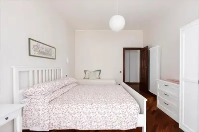 a white bedroom with a bed with a floral bedspread at Anton Inn Rome Cornelia Apartment in Rome