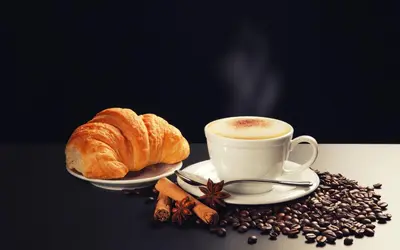 a cup of coffee and a croissant and coffee beans at Residenza Dorò- 24x7 Check-in in Rome