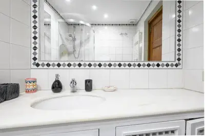 a white bathroom with a sink and a mirror at Roman Forum Apartment - The Heart of Rome in Rome