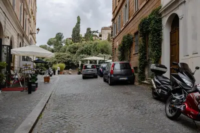 a cobblestone street with parked cars and buildings at Roman Forum Apartment - The Heart of Rome in Rome