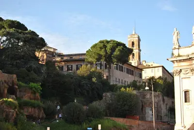 a building on a hill with a tree in front of it at Roman Forum Apartment - The Heart of Rome in Rome