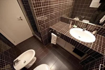a black tiled bathroom with a sink and a toilet at Star of Rome in Rome