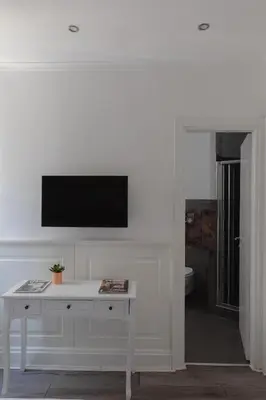a white living room with a tv on a wall at Relais Roma Centro in Rome