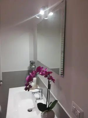 a bathroom with a sink with a vase with purple flowers at Vic Pigneto, Luxury House Terrace Roma in Rome