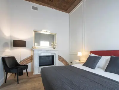 a bedroom with a bed and a chair and a fireplace at Gemini Suites Navona in Rome