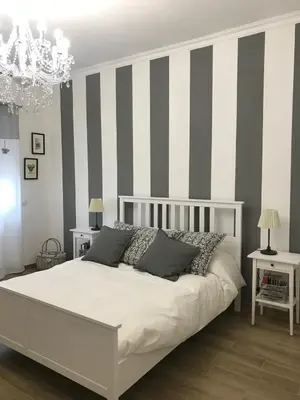 a bedroom with a white bed with striped walls at Da Nonna Maria in Rome