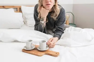 a woman sitting on a bed with two cups and a wooden tray at Trevi Fountain Apartment - ZENO 03 in Rome